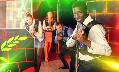 portrait of smiling men and women co-workers having corporate entertainment in laser tag room