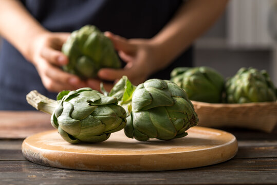 Green artichoke on wooden board prepare for cooking, Edible flower bud