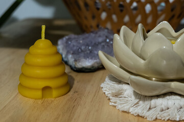 A beehive votive shaped beeswax candle is displayed next to a crystal and flower shaped candle holder. - obrazy, fototapety, plakaty