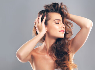 Her hair is her crowning glory. Studio shot of a beautiful young woman posing against a gray background.