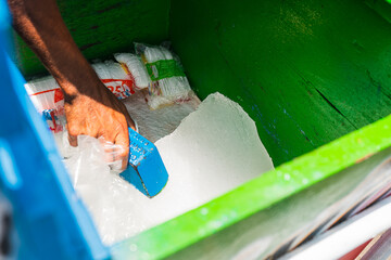 Close-up of the hand of a street vendor scraping ice inside his cart on the beach in the summer...