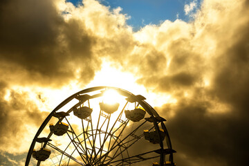 Attraction ferris wheel in stormy red clouds.