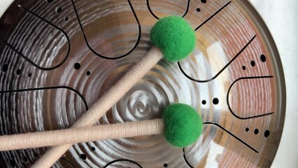 A musical instrument, a glucophone, a drum with a metal tongue on a wooden background. A modern musical instrument with wooden sticks. A tool for meditation, relaxation, with a deep magical sound