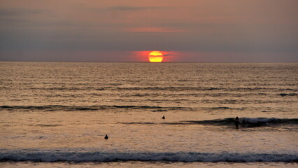 Sunset over the beach in Canoa, Ecuador, silhouetting swimmers