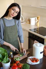 Young asian vegan woman cutting vegetables in the kitchen. Compost bucket. Eco friendly person.