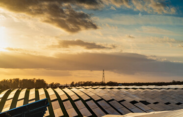 UK Solar Park and electricity pylon,at sunset,vibrant golden sunlight reflecting from panels,Hampshire,England,United Kingdom.