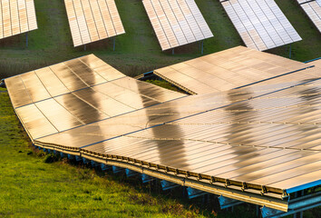 Details of light sensative panels at UK Solar Park,angled towards the sun,reflecting golden sunlight,Hampshire,England,United Kingdom.