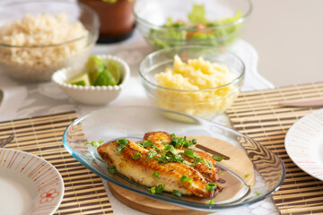 Lunch at the table with grilled tilapia with mashed potatoes and salad accompanied by rice