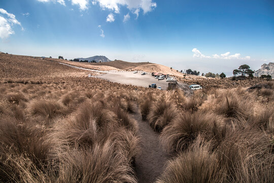 Landscape with parking area surrounded by yellow grass with a blue sky in Paso de Cortés in Mexico - Powered by Adobe