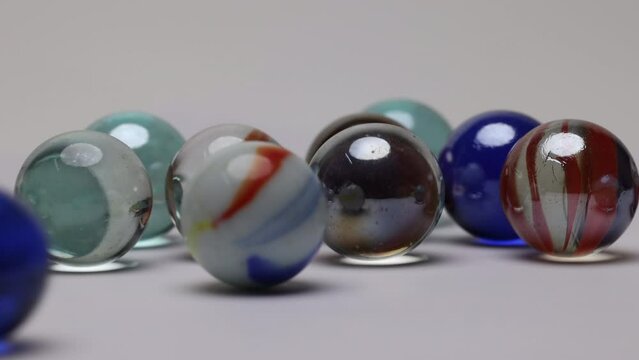 Glass marble balls playing rolling hitting clashing on white background 