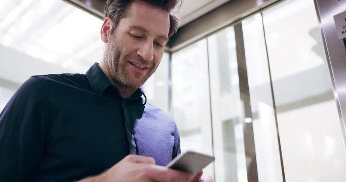 I'll meet you in the lobby. Handsome mature businessman sending a text while riding the elevator at work. Business man texting at work 