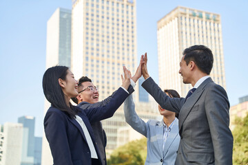 asian businesspeople celebrating success with high-fives