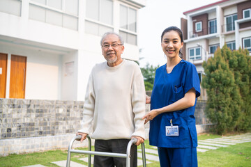 Portrait of Asian caregiver nurse support senior male walking outdoors