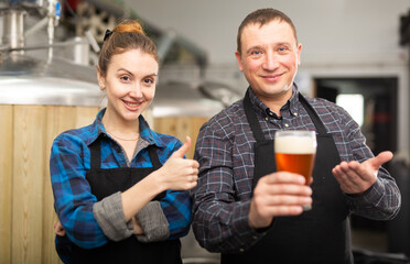 Satisfied man and woman - brewery owners with glasses of beer