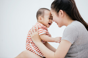 Asian mom enjoy with baby adorable on the bed is smiling and happy. Happy family. Unconditional love infant baby.