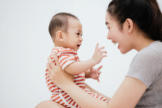 Asian Mom Enjoy With Baby Adorable On The Bed Is Smiling And Happy. Happy Family. Unconditional Love Infant Baby.