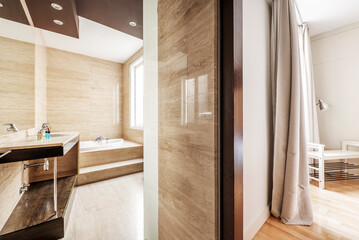 Bathroom with whirlpool tub and polished marble cladding and hardwoods in an en-suite bedroom