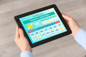 Young woman with tablet computer using weather forecast application, closeup