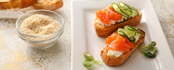 Woman sprinkling sesame seeds onto tasty bruschettas with cheese, salmon and cucumber on plate