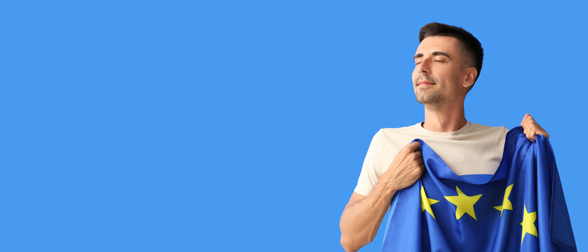 Young man with flag of European Union on blue background with space for text