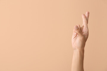 Male hand with crossed fingers on color background