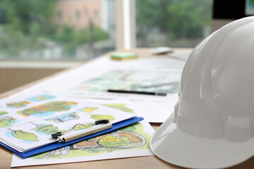 Landscape designer's projects with hardhat on table in office