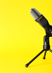 Stand with modern microphone on yellow background