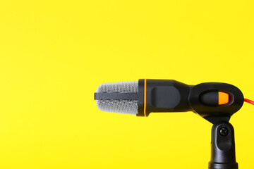 Stand with modern microphone on yellow background