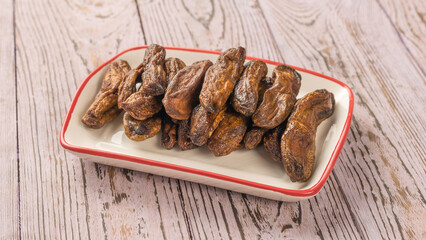 Ceramic white cup with dried bananas on a wooden table.