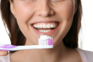 Young woman and tooth brush with paste on white background, closeup