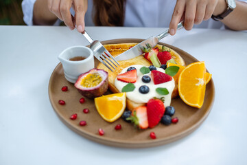 Closeup of a woman eating mixed fruits french toast brunch in restaurant