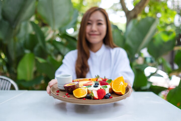 Blurred of a young woman holding a plate of mixed fruits french toast brunch in restaurant