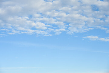Peaceful blue sky with puffy white clouds, as a nature background
