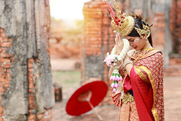 Young beautiful asian woman in red Thai traditional costume pay respect sawasdee symbol with...