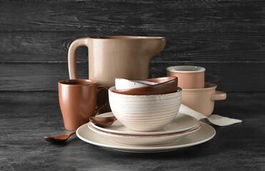 Set of stylish dinnerware on dark wooden background