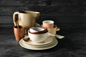 Set of stylish dinnerware on dark wooden background