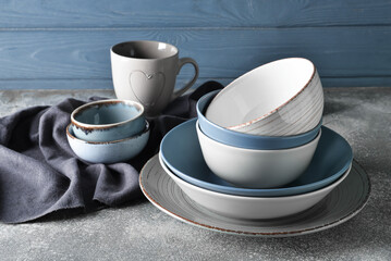 Set of stylish dinnerware on grey wooden background