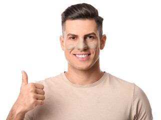 Handsome man with applied clay mask showing thumb-up on white background