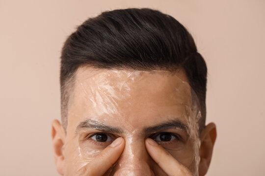 Handsome man with gel mask on beige background, closeup