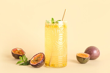 Glass of delicious passion fruit juice on yellow background