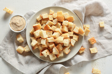 Plate with tasty croutons, sauce and napkin on white background