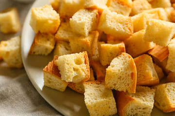 Plate with tasty croutons on light napkin, closeup