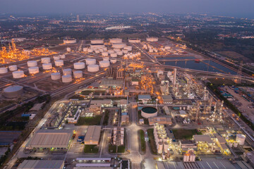 Aerial view of petrochemical oil refinery and sea in industrial engineering concept in Bangna district at night, Bangkok City, Thailand. Oil and gas tanks pipelines in industry. Modern metal factory.