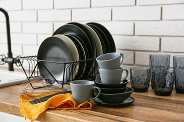 Modern black dinnerware on counter near white brick wall
