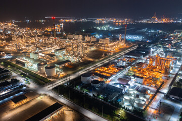Aerial view of petrochemical oil refinery and sea in industrial engineering concept in Bangna district at night, Bangkok City, Thailand. Oil and gas tanks pipelines in industry