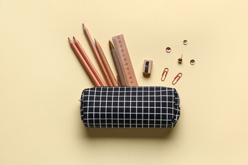 Pencil case with school stationery on color background, top view