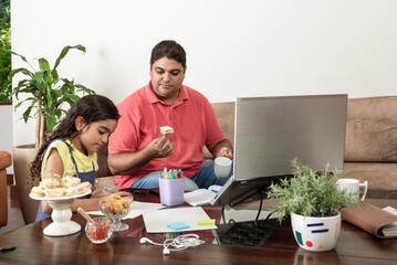 Pai trabalhando com filha fazendo dever de casa na sala de estar