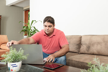 Homem jovem brasileiro em video chamada desde casa com laptop