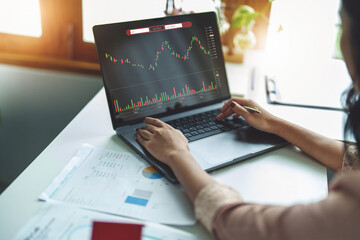 Financial and investment planning concept, female businesswoman using computer to analyze charts to find entry points on a trading board. through digital media via the internet.