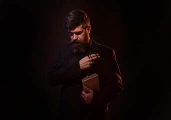 Praying hands priest portrait of male pastor. Man in suit with a Bible. Pastor or preacher praying,...